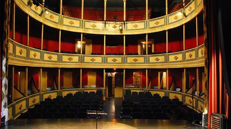 Tomt teater sett fra scenen med buede gallerier og røde vegger.