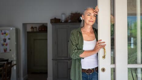 Kvinne står i en dør og ser ettertenksomt ut
