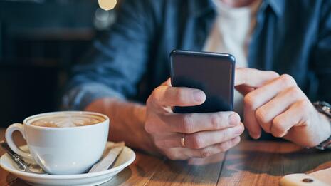 Nærbilde av mobiltelefon og kaffekopp 