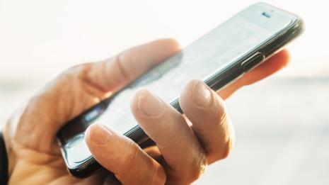 Person bruker mobil for å få tilgang til forsikringstjenester hos Tryg