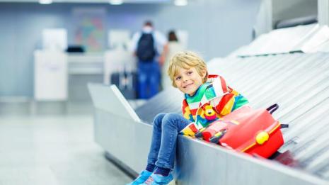 Barn sitter på bagasjebåndet