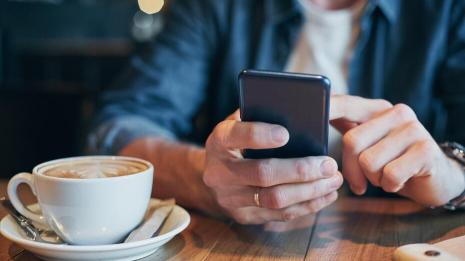 Nærbilde av mobiltelefon og kaffekopp 