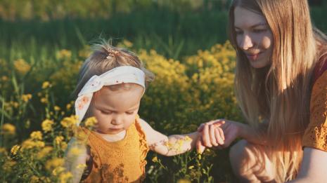 Mor og baby sitter i en blomstereng