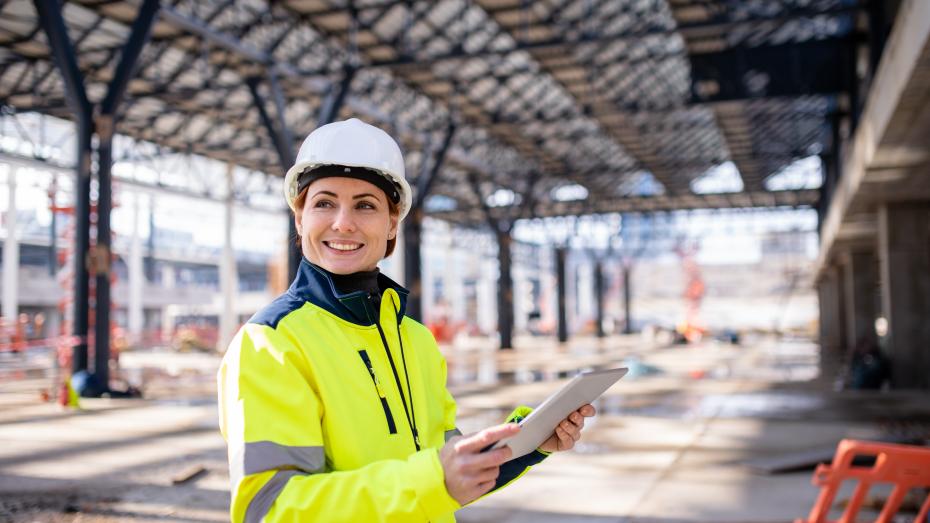 En dame i gule arbeidsklaer pa arbeidsplass. Foto