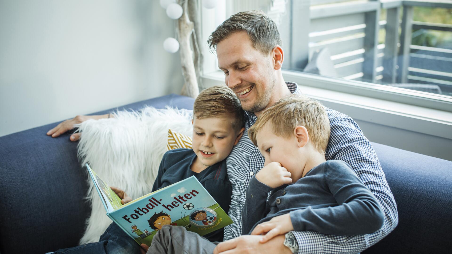 Far og to sønner leser bok