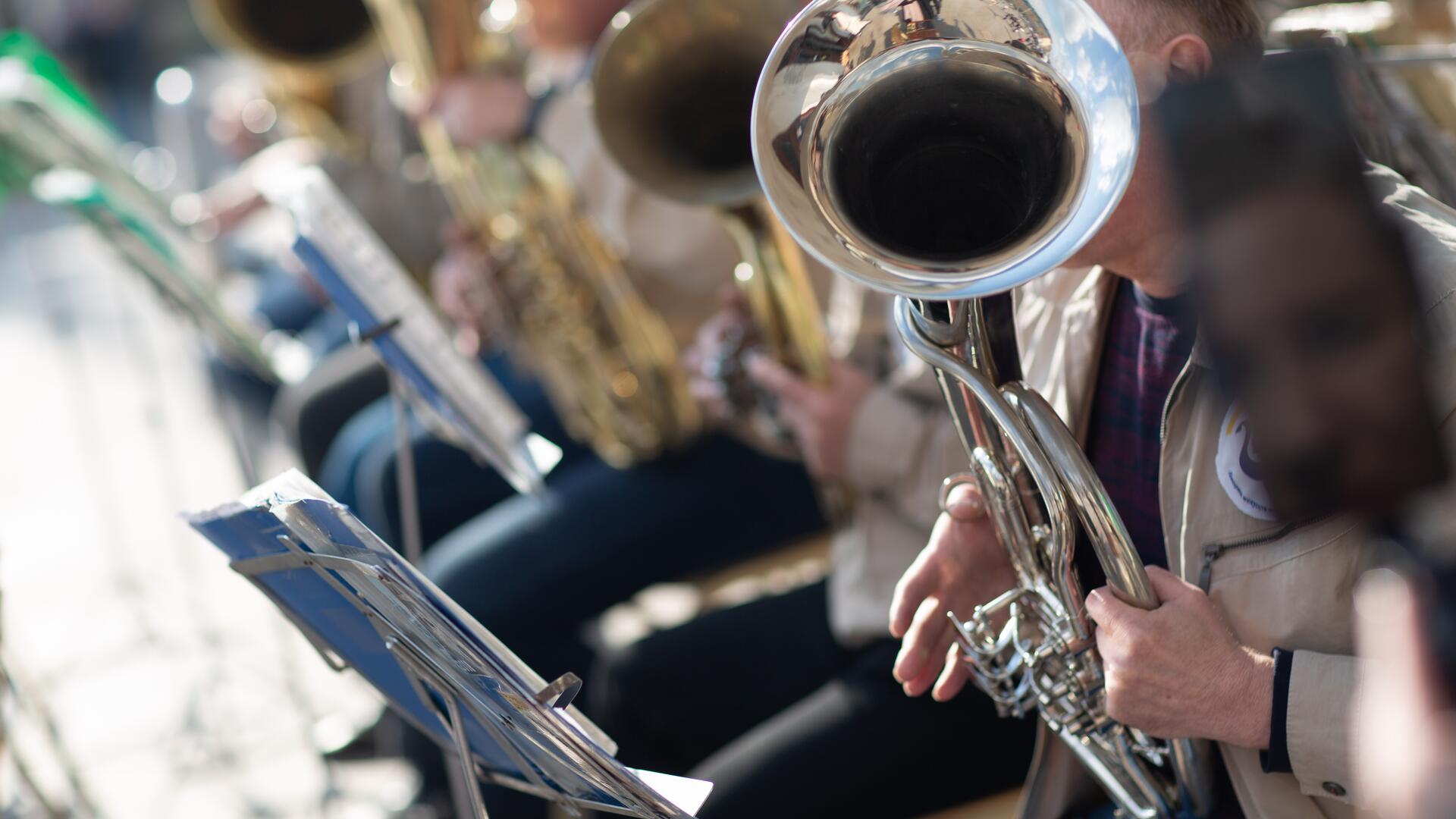 Musikere spiller på tubaer utendørs i et korps