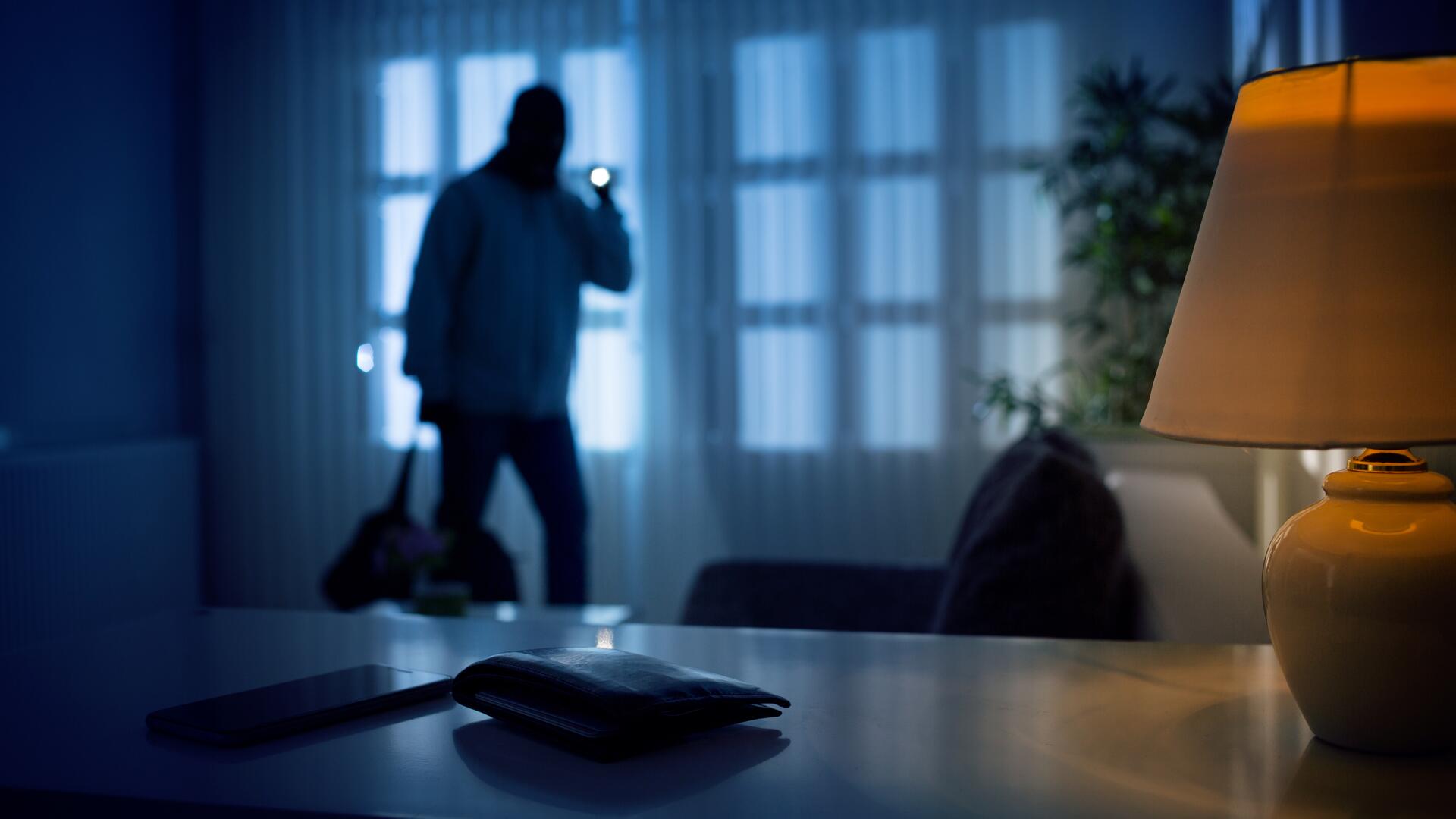 Innbruddstyv med lommelykt inne i et mørkt hjem