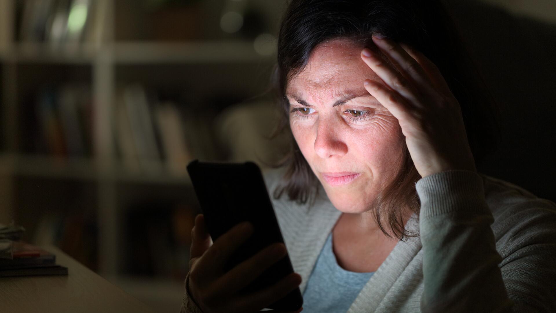 Bekymret kvinne ser på mobiltelefonen sin