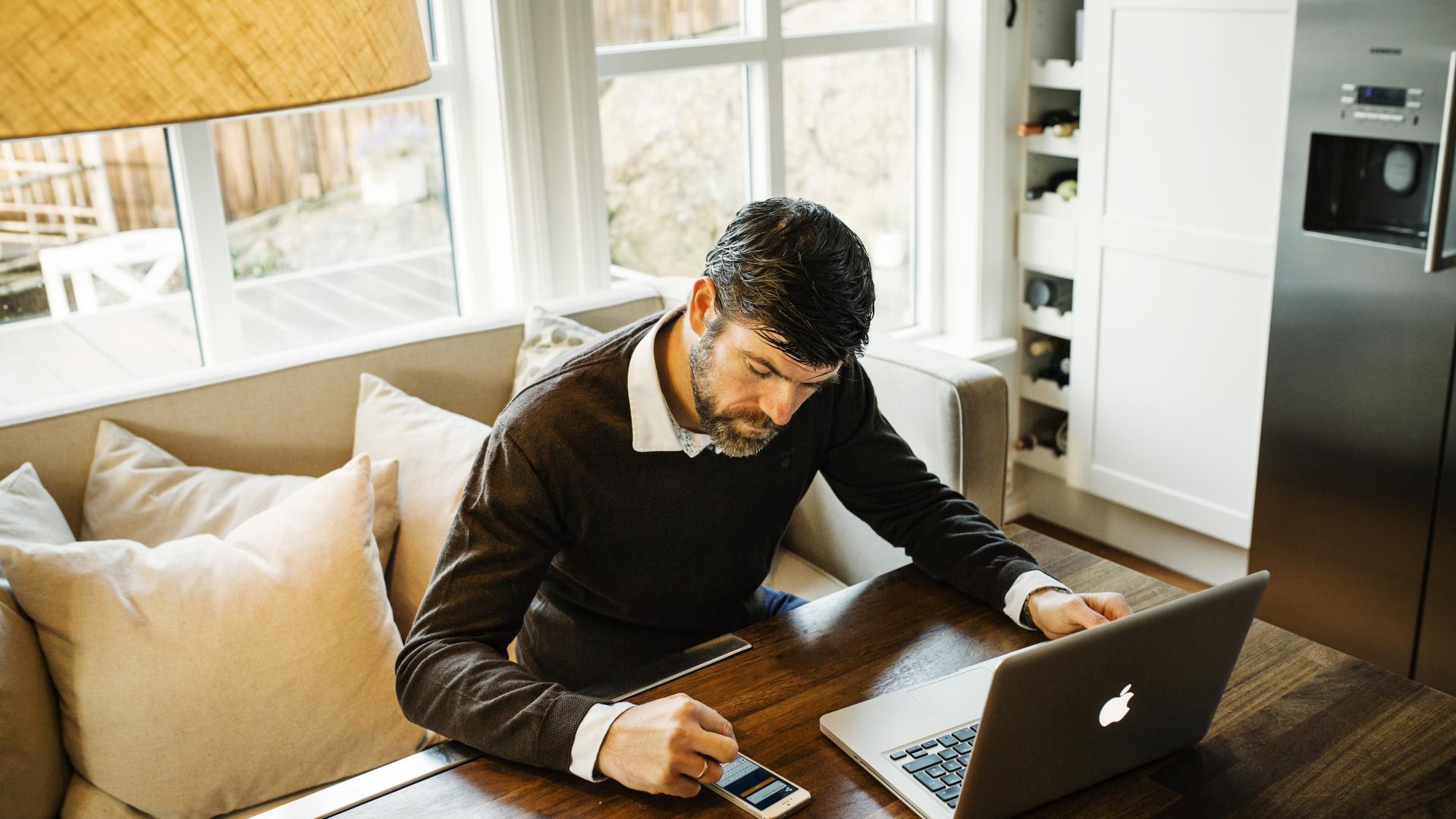 Mann som jobber med pc-en og telefon hjemme