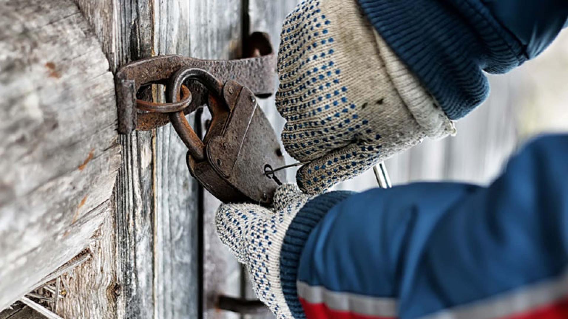 Mann som dirker opp låsen på en hytte 