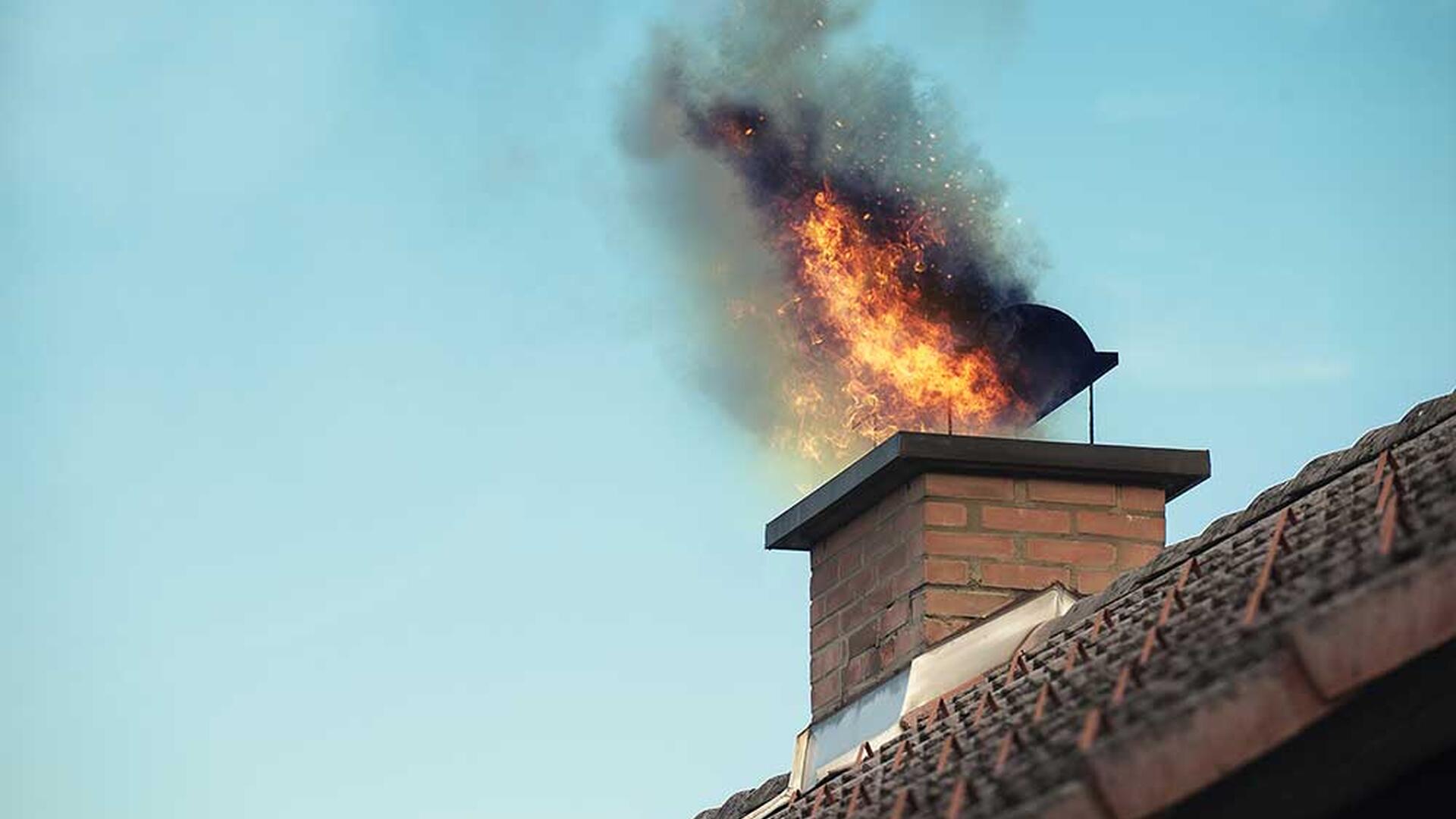 Pipebrann med flammer og røyk som kommer ut av skorsteinen på et hus.