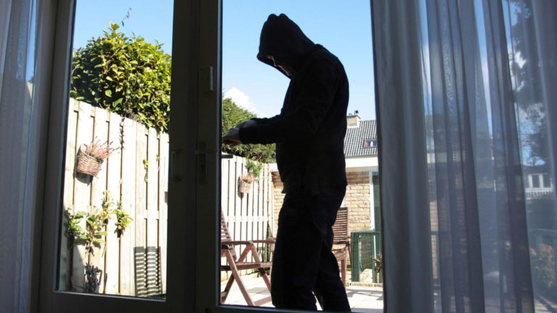 Innbruddstyv bryter seg inn en skyvedør av glass