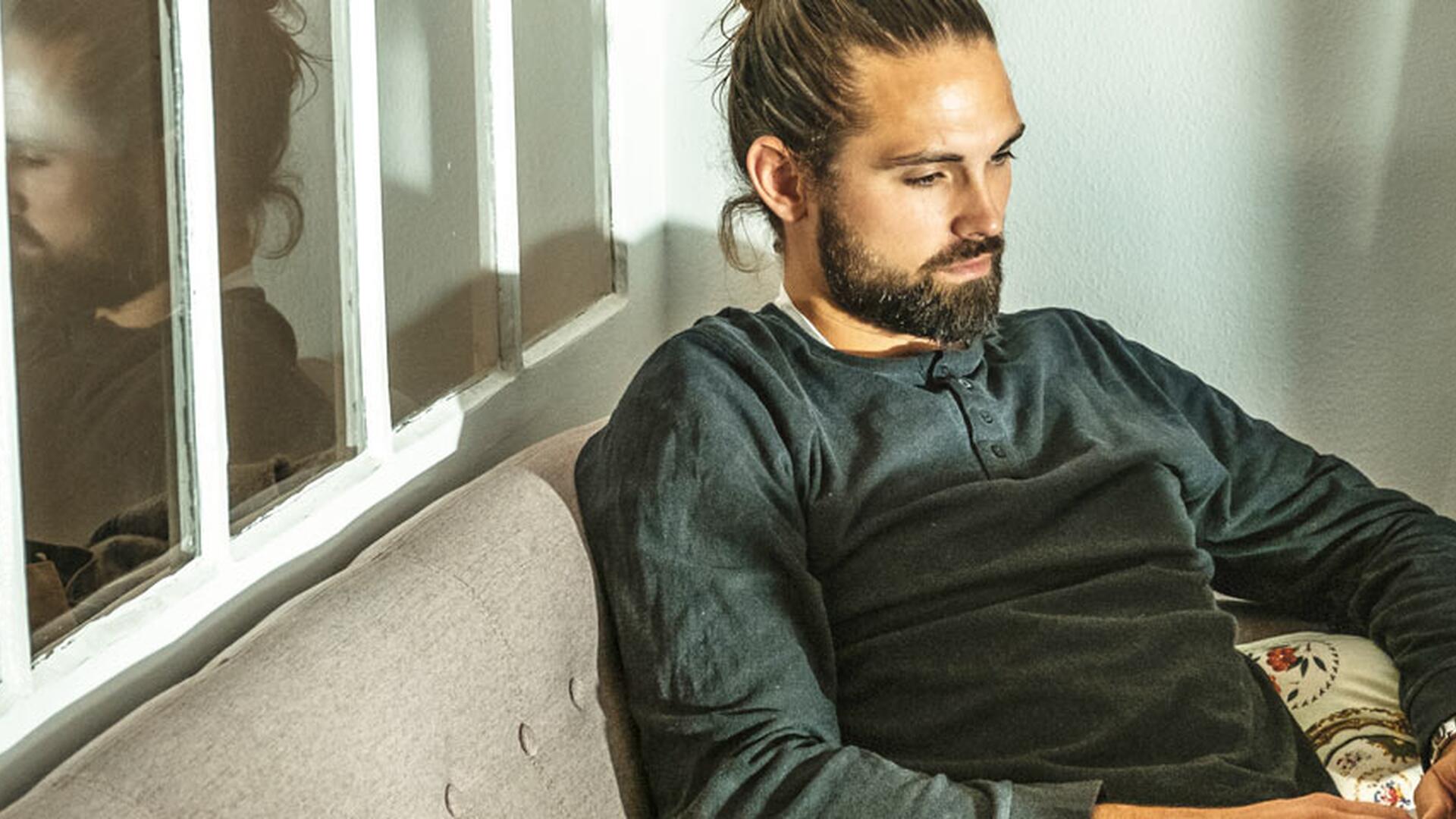 Student med mørk genser sitter i sofa med laptop på fanget.
