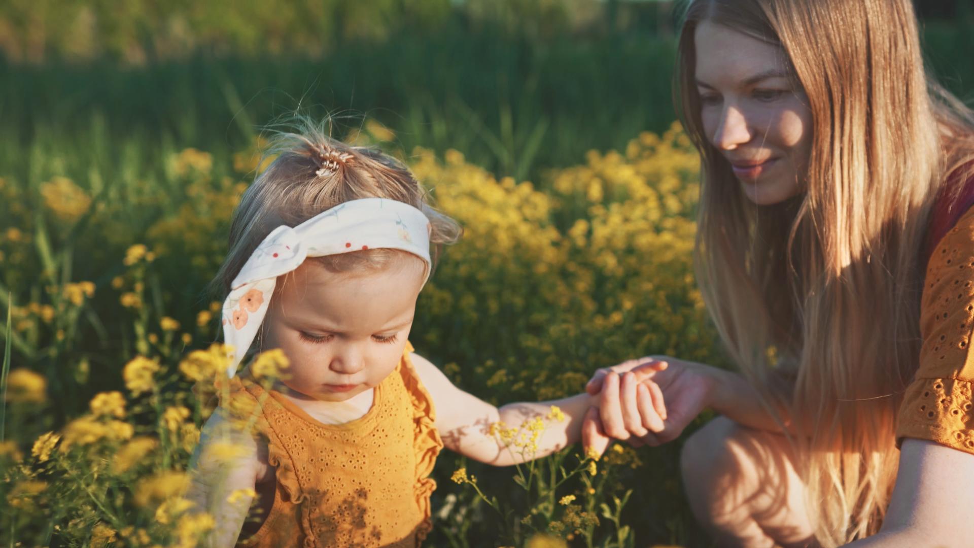 Mor og baby som sitter i en blomstereng - personforsikring