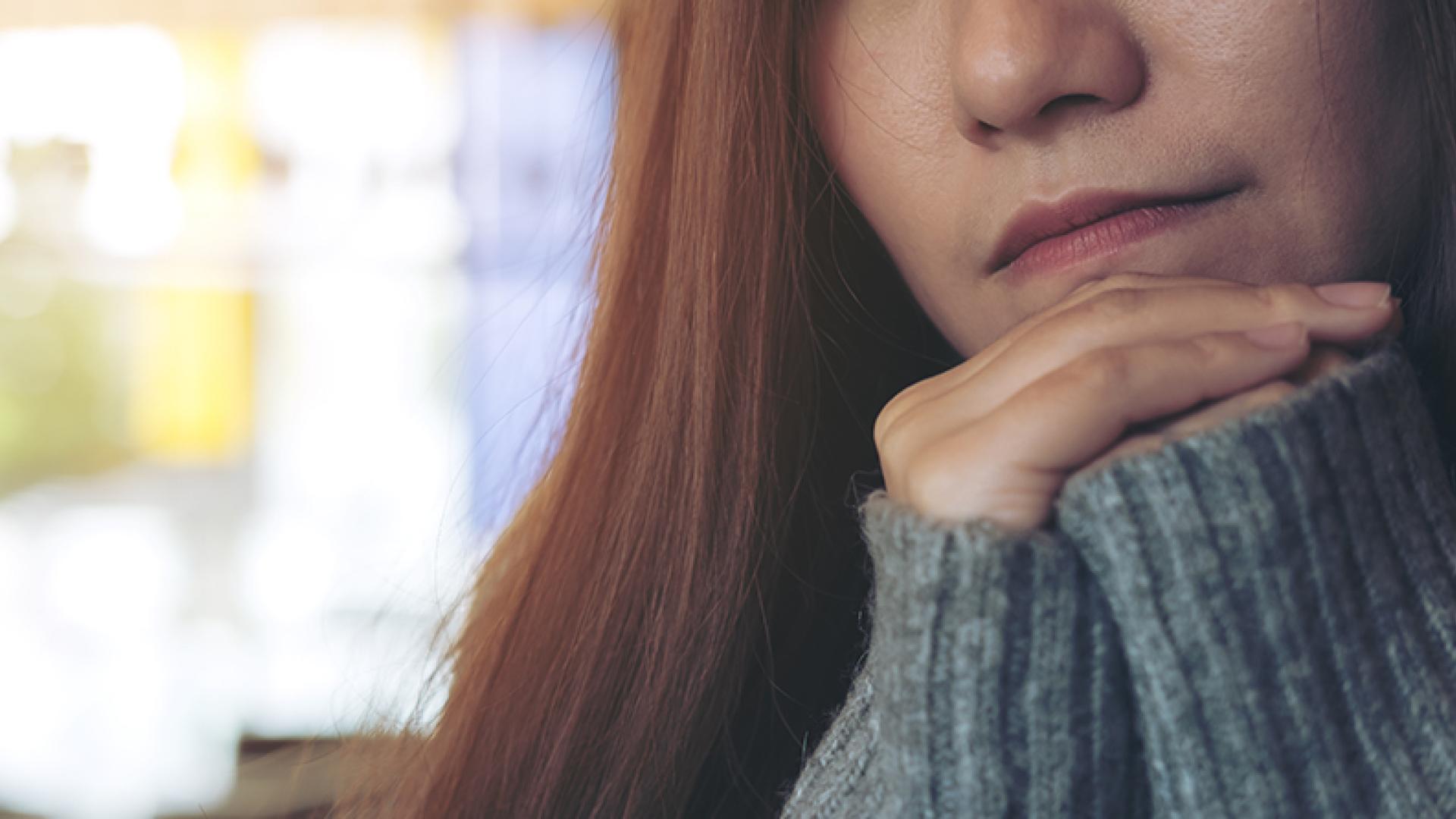 Kvinne hviler hodet i hendene