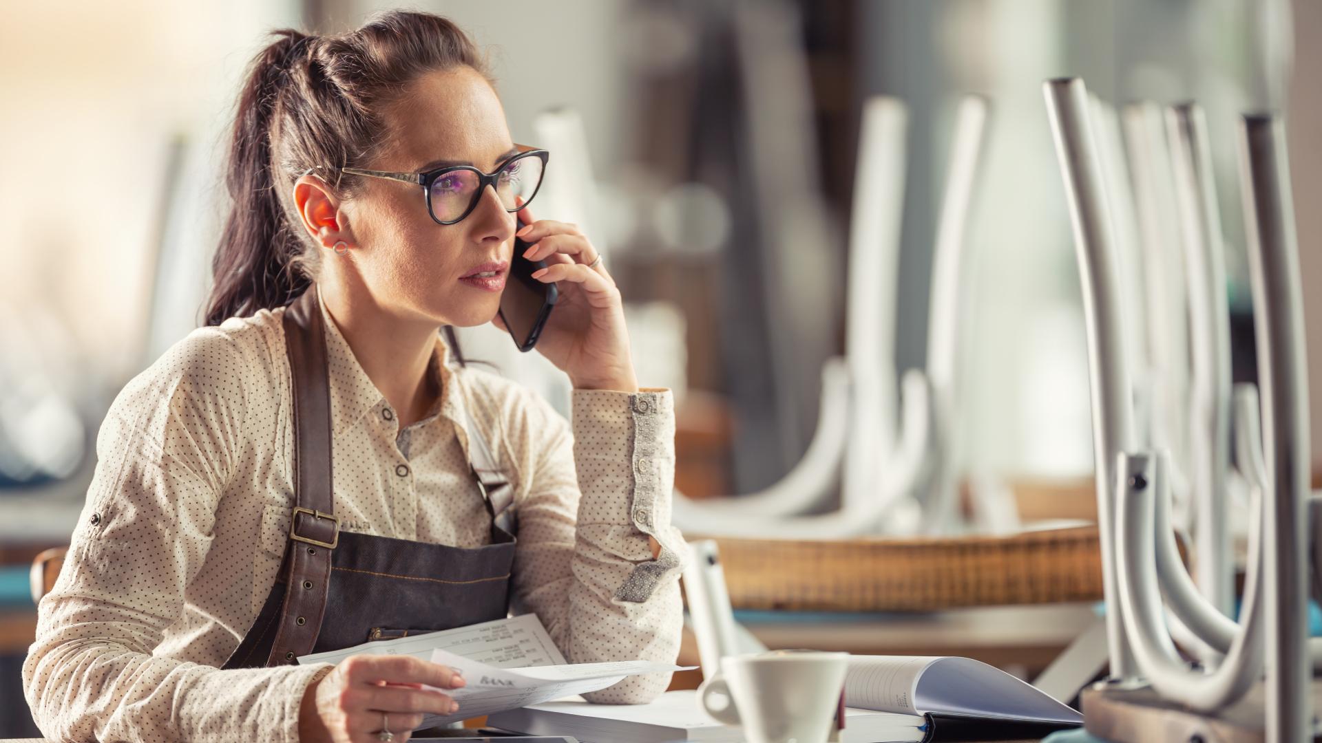 Kvinnelig ansatte ser på papirer og er i telefonen