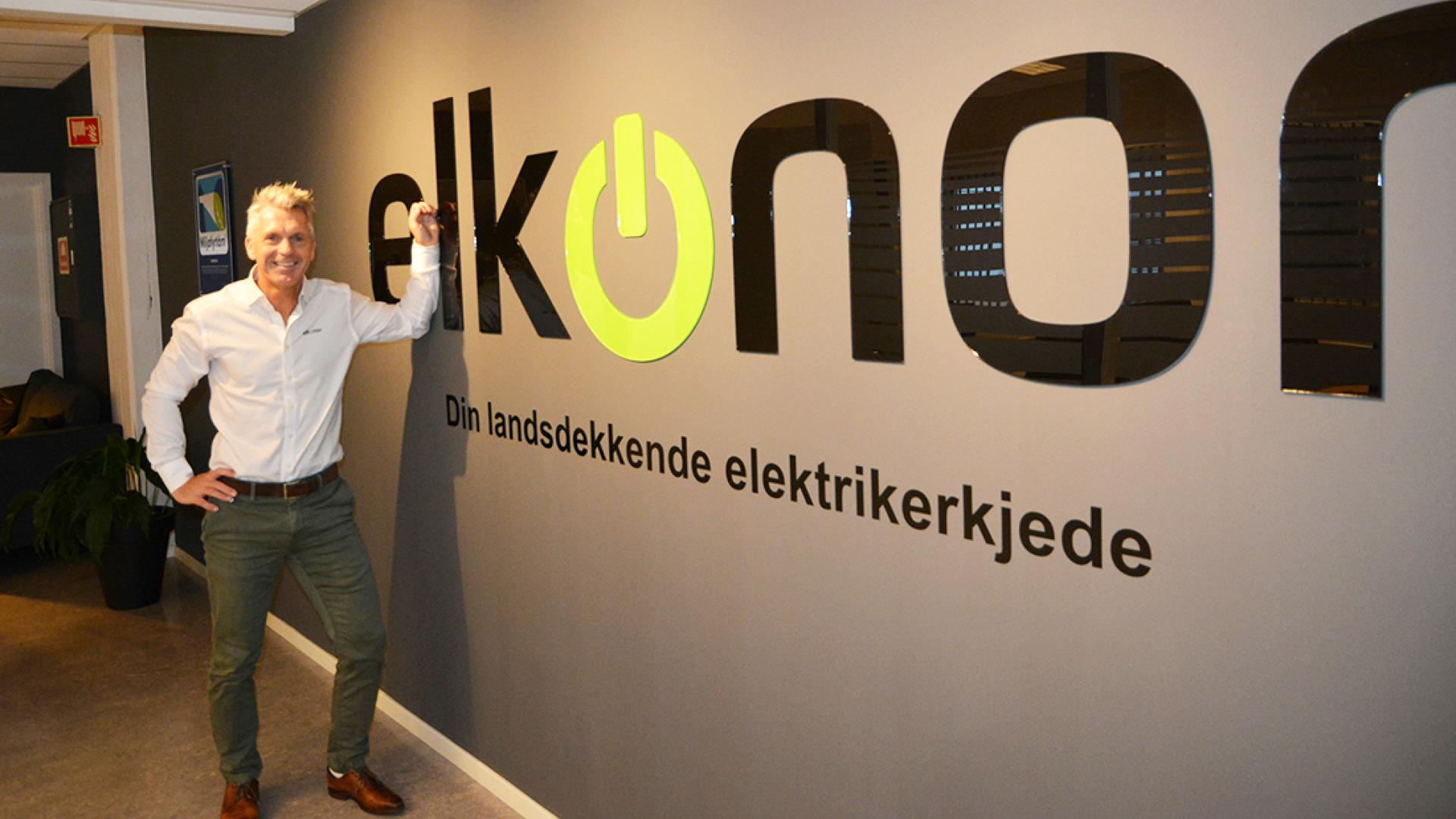 Baard fra Elkonor star foran en vegg med logo. Foto