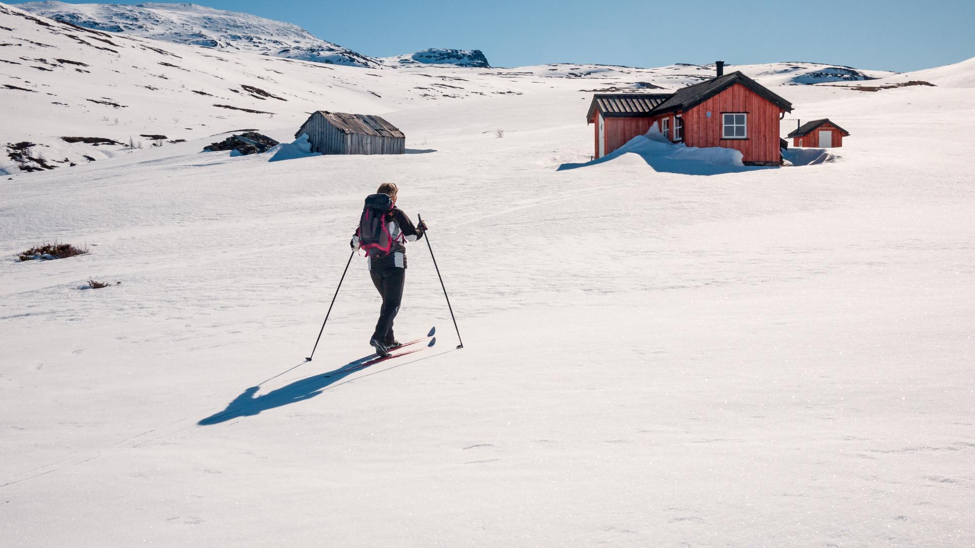 En som står på ski til hytten