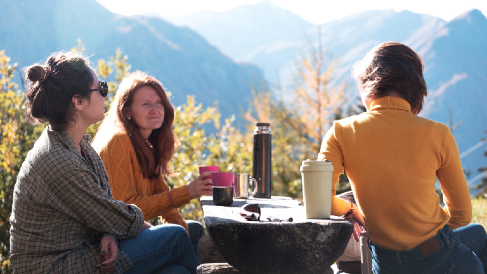 Tre venner som har gått fjelltur og tar seg en pause med kaffe