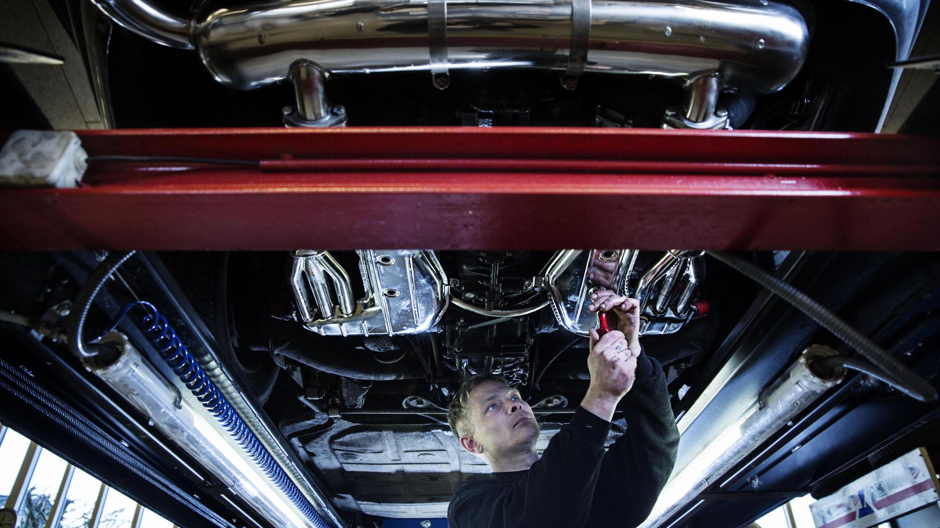 Mann som jobber under en bil