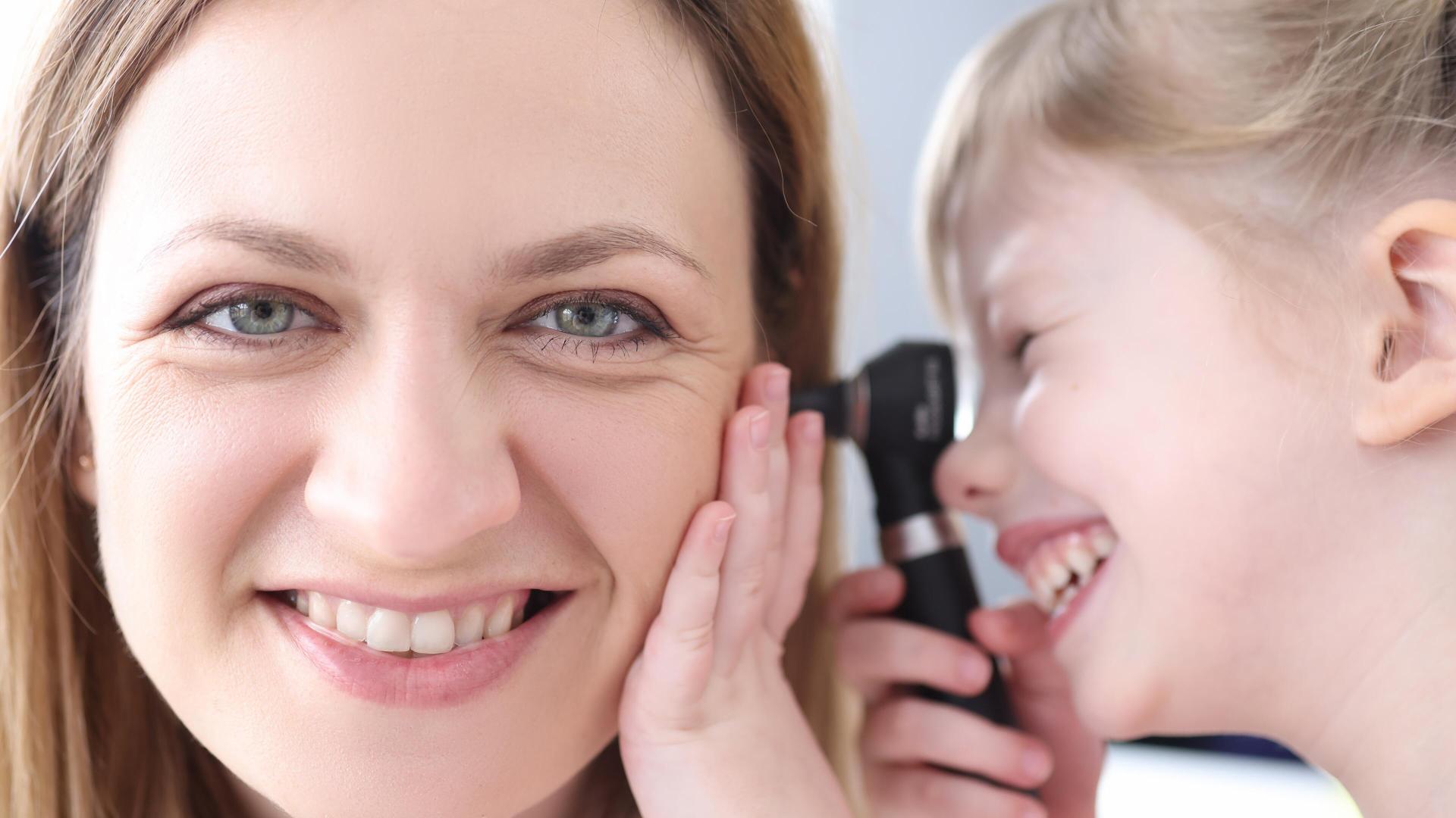 En jente ser inn i øret til en voksen