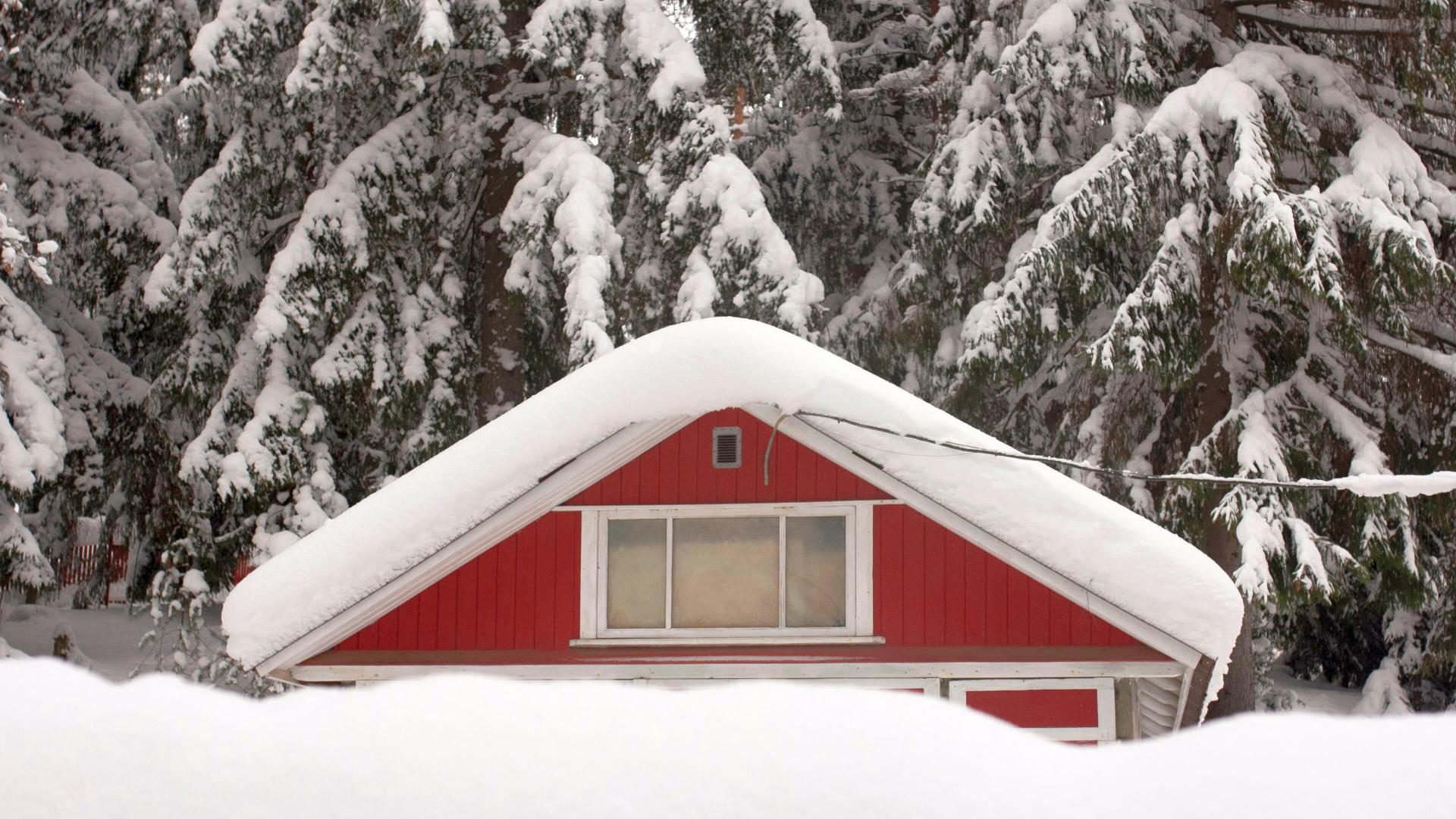 Rød hytte med snø på taket