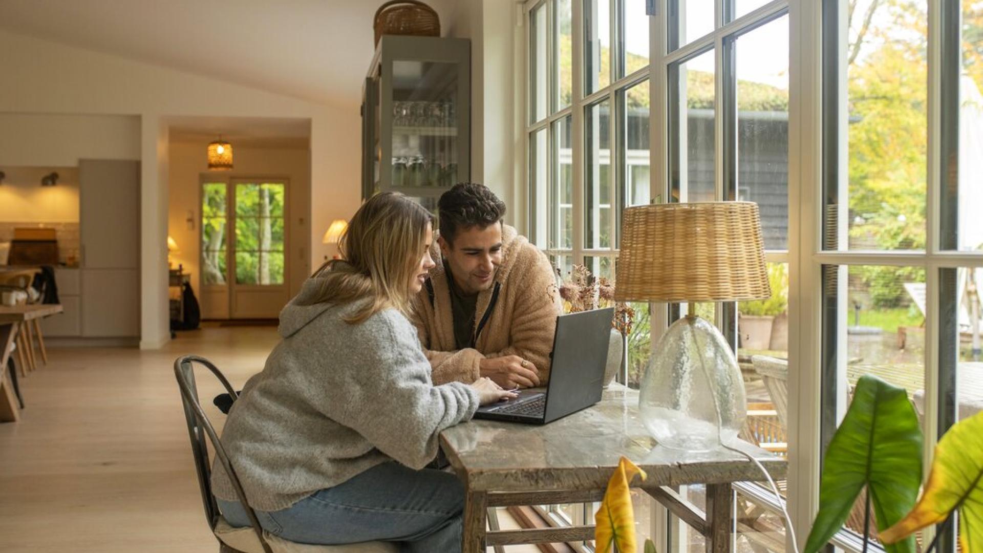 Ungt par sitter ved bærbar PC/datamaskin