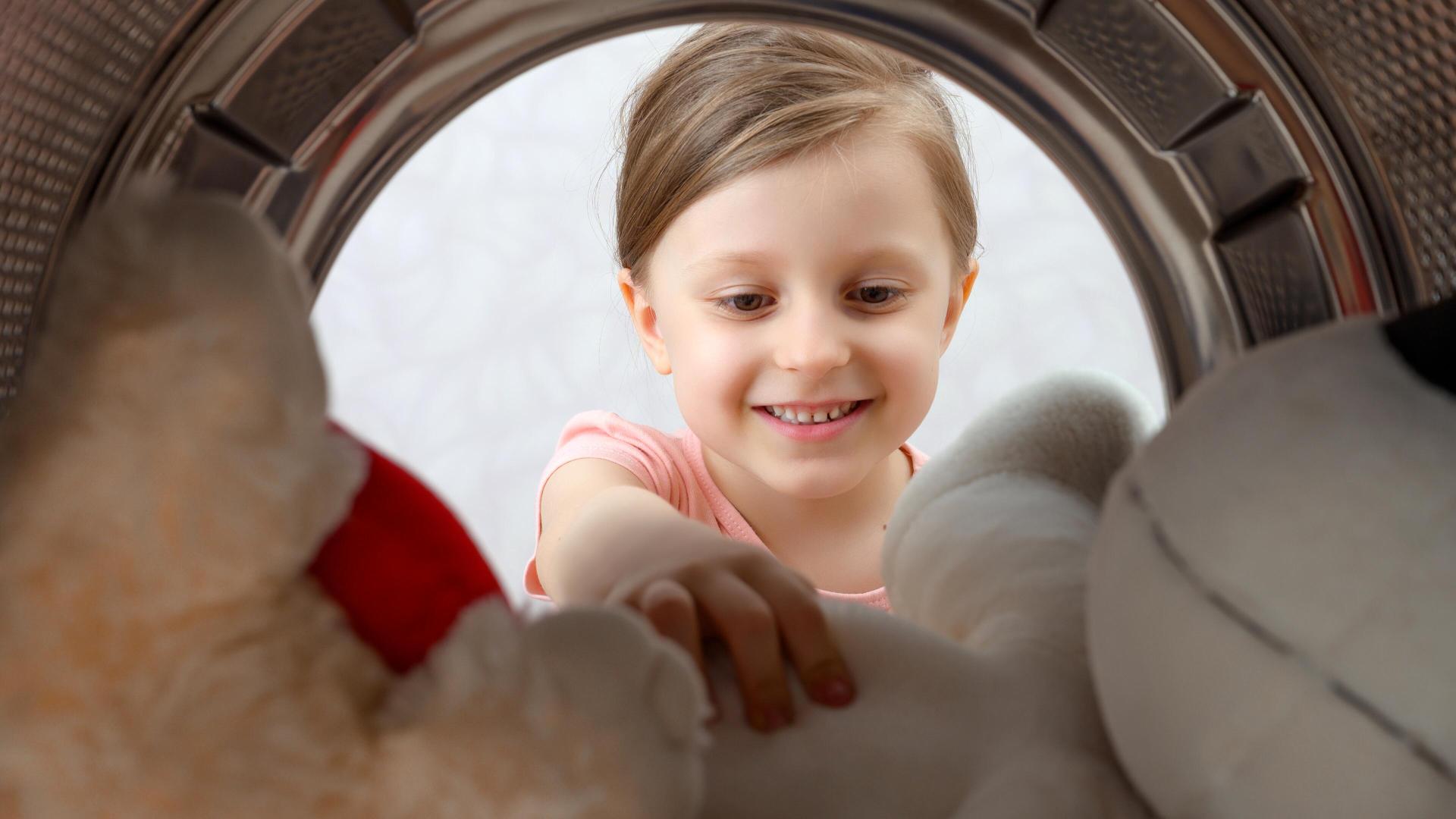 Jente ser inn i vaskemaskin