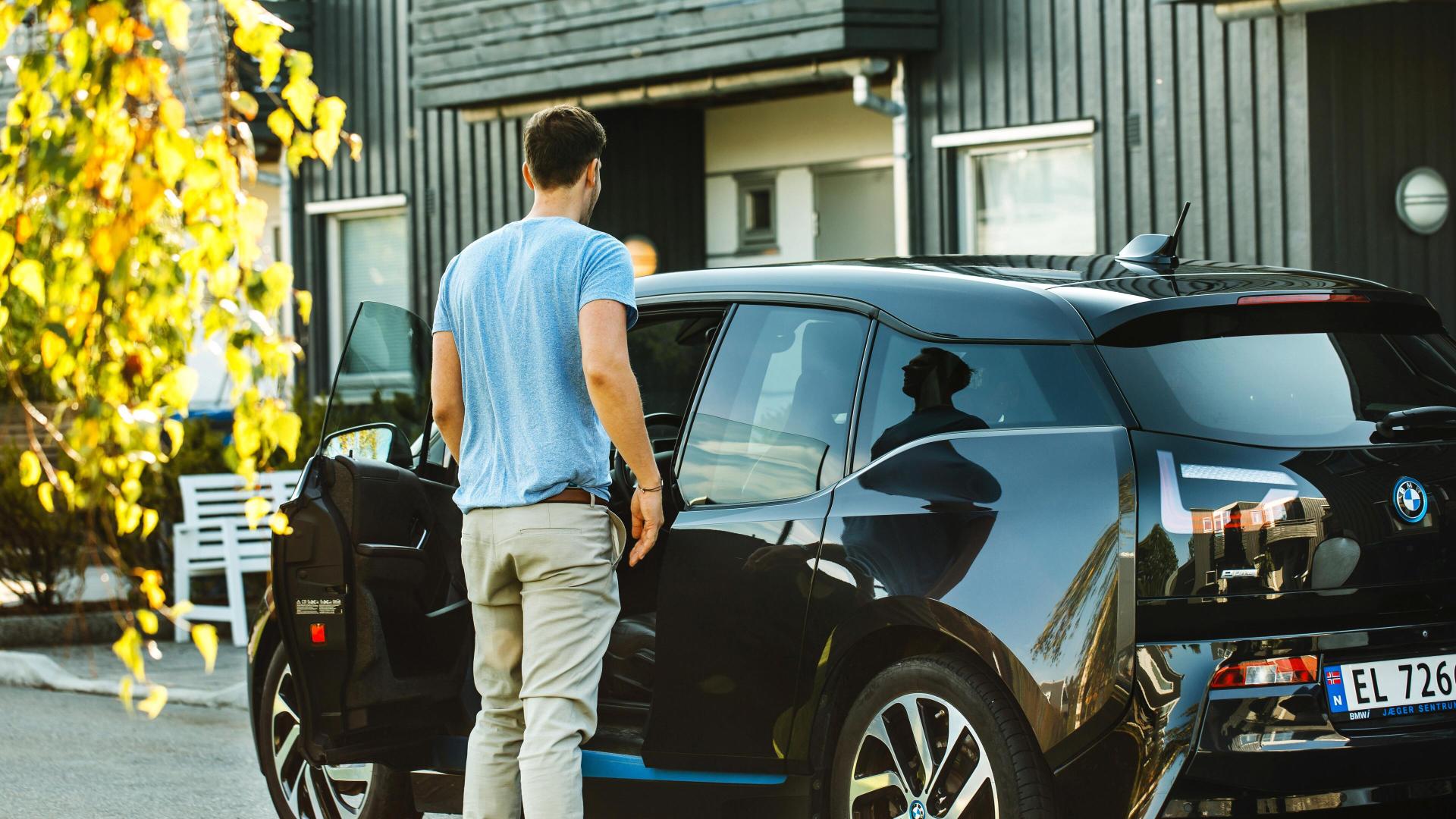 Mann som skal sette seg inn i en elbil med elbilforsikring fra tryg