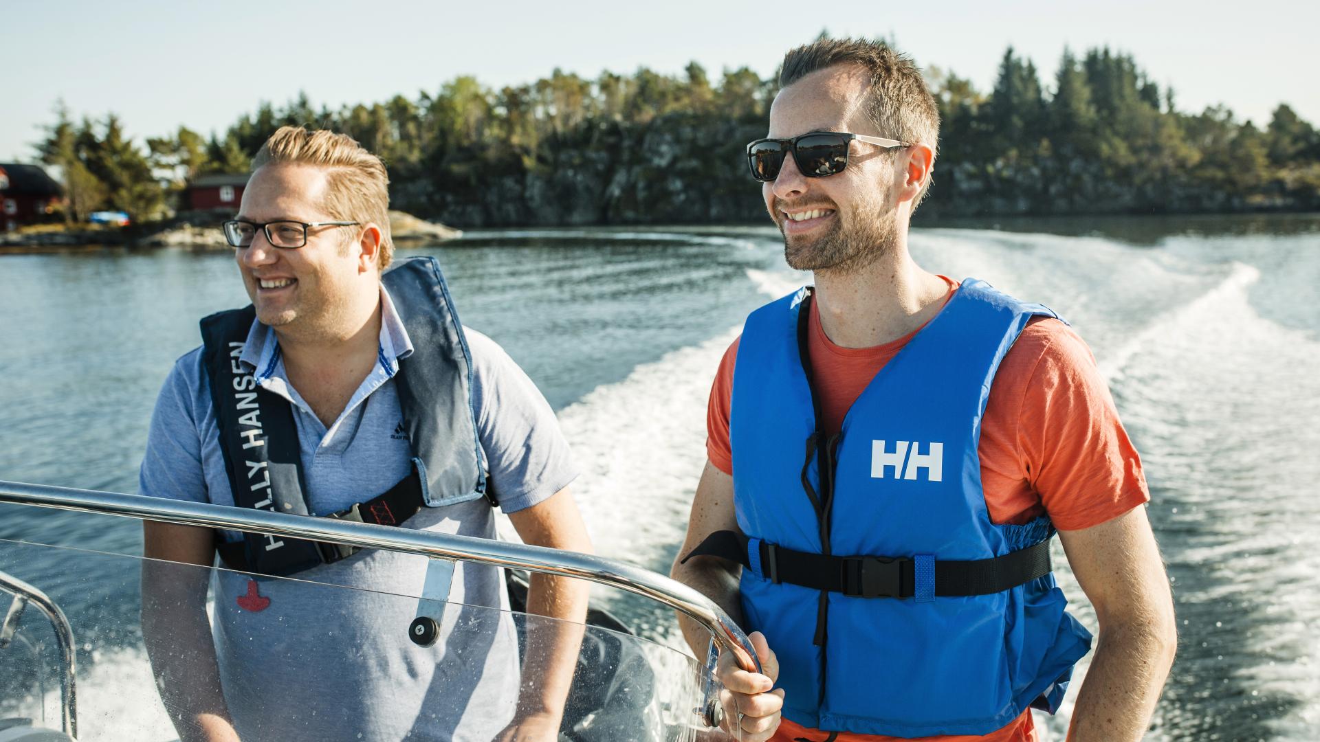 To smilende menn i åpen båt på sjøen