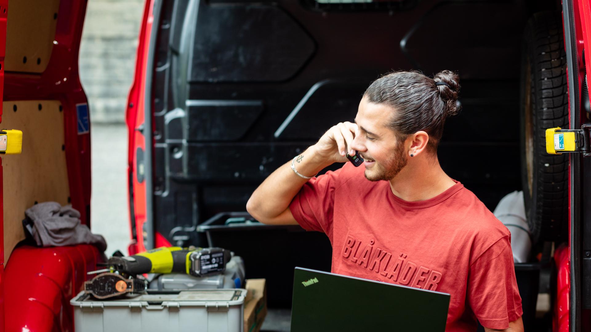 Handverker sitter i firmabil og prater i telefon