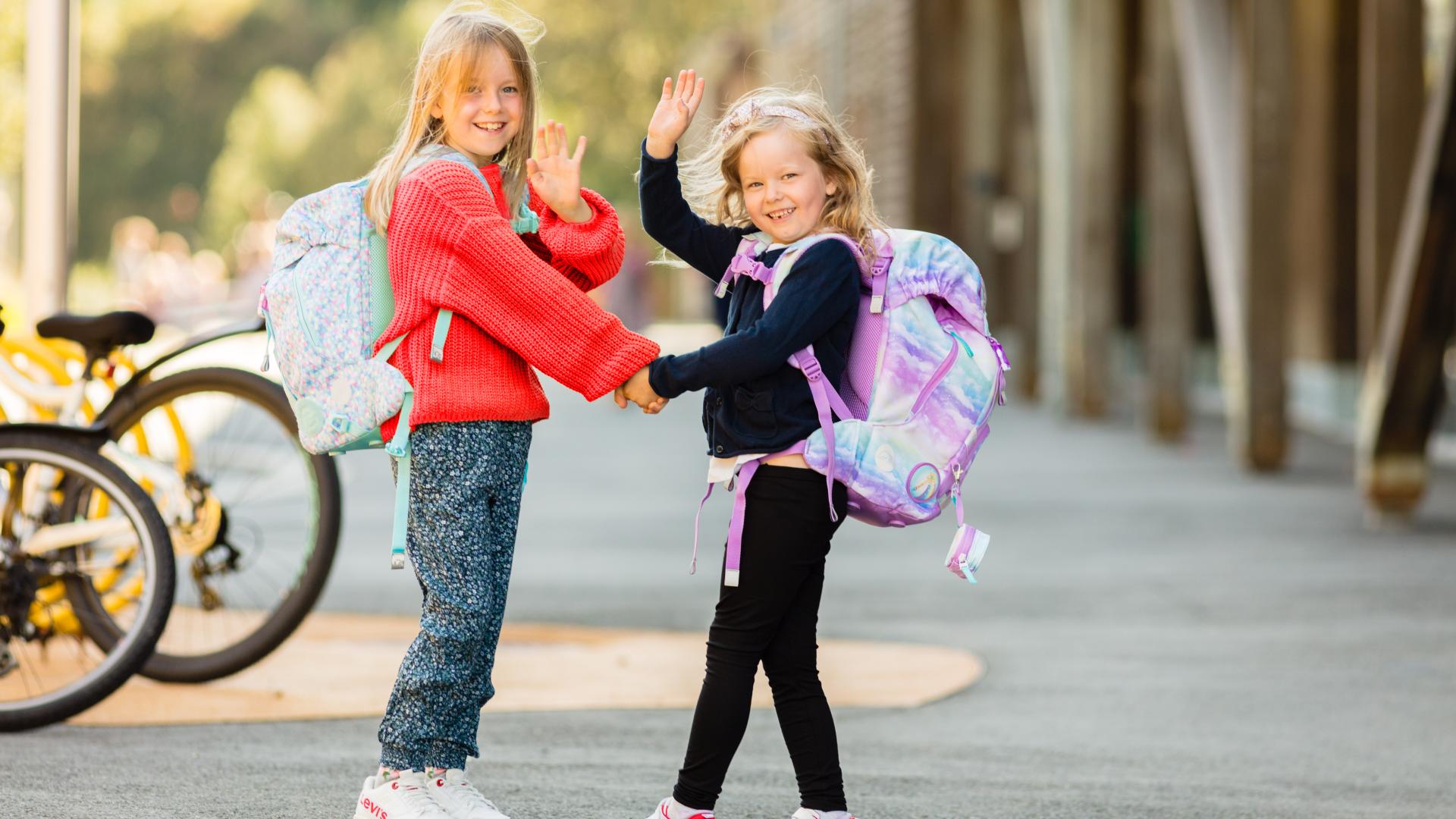 To unge veninner som holder hender og går til skolen sammen 